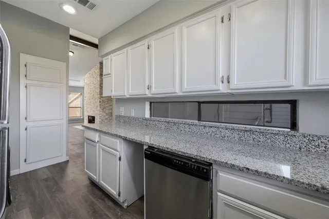 a kitchen with granite countertop white cabinets and sink