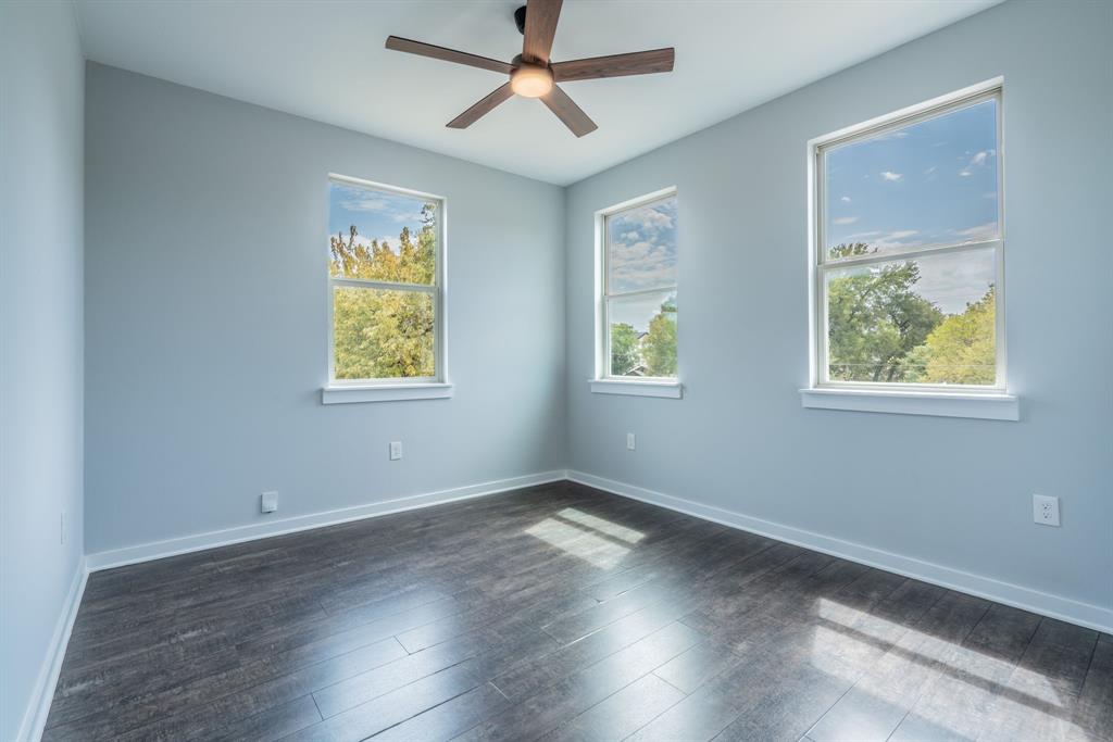 3610 Vilbig Road Dallas, TX 75212 - Photo 14 of 29 Wood-finish flooring, three double-hung windows, light-toned walls, and a ceiling fan with integrated lighting