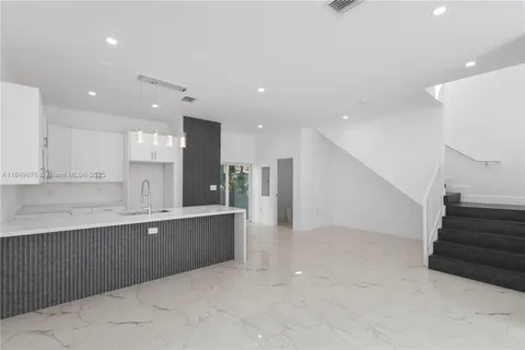 a large kitchen with stainless steel appliances granite countertop a large counter top a sink and a refrigerator