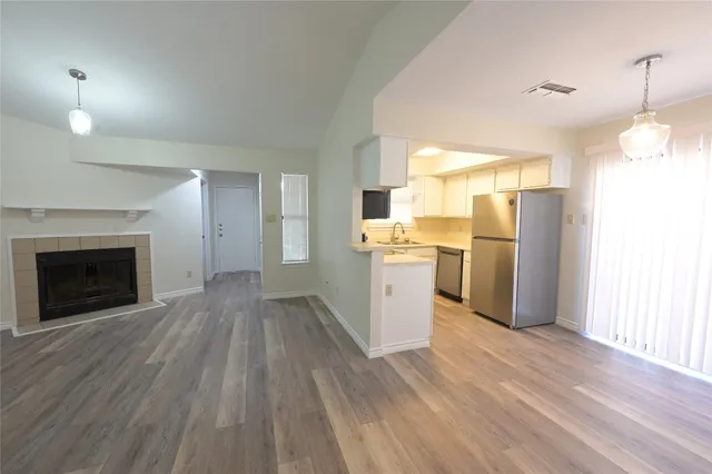 a view of empty room with wooden floor and kitchen view