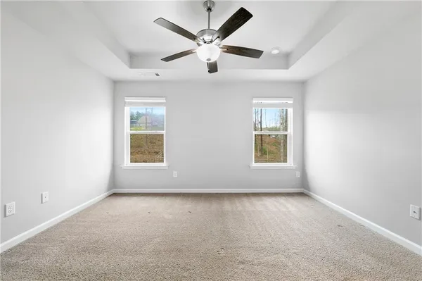 an empty room with ceiling fan and windows