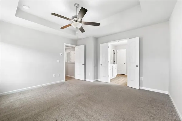 a view of a livingroom with a ceiling fan & windows