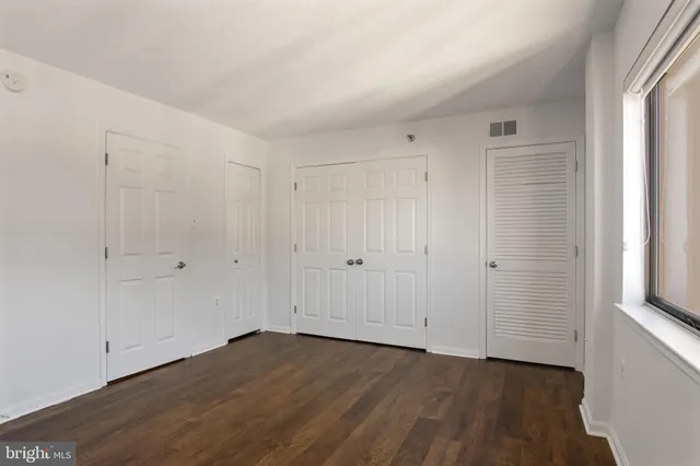 a view of a hallway with wooden floor and a bathroom