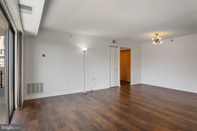 a view of an empty room with a window and wooden floor