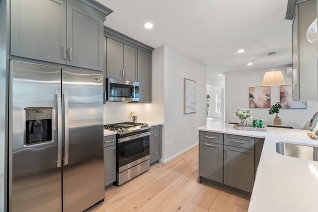 a kitchen with kitchen island granite countertop stainless steel appliances and wooden cabinets