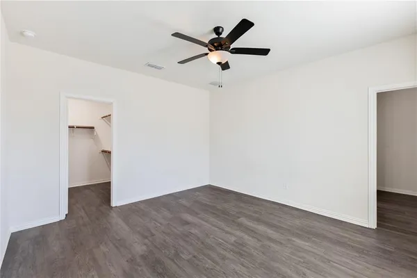 an empty room with wooden floor and ceiling fan