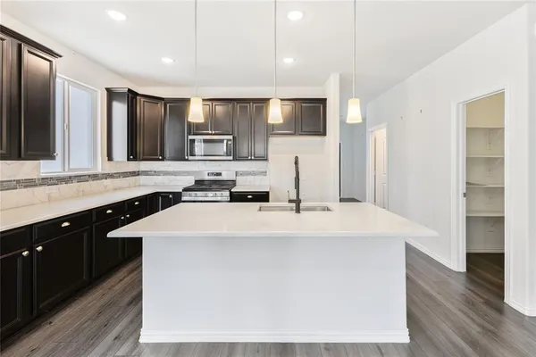 a large kitchen with kitchen island a sink dishwasher a refrigerator and a stove with wooden floor