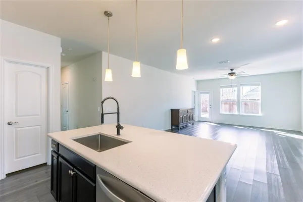 a kitchen with a sink and entryway with wooden floor