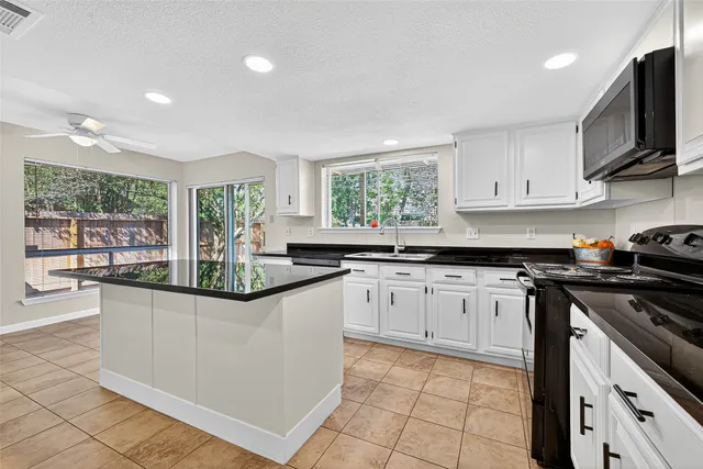 a kitchen with granite countertop a stove sink and cabinets