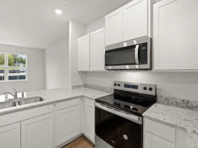 a kitchen with granite countertop white cabinets and a window