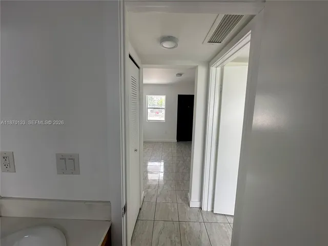 a view of a hallway with a livingroom and a bathroom with sink
