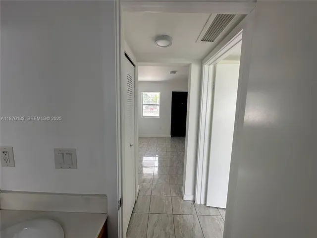 a view of a hallway with a livingroom and a bathroom with sink