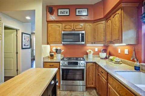 a kitchen with stainless steel appliances a stove a sink a microwave a refrigerator and cabinets
