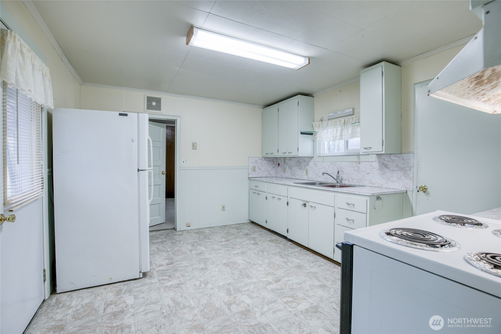 1019 Maple Street Hoquiam, WA 98550 - Photo 10 of 21 a view of a kitchen with refrigerator and white cabinets
