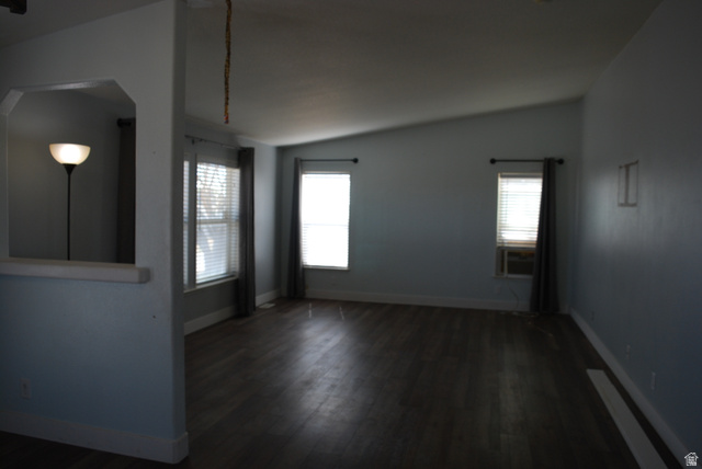 1055 West Ashby Road Delta, UT 84624 - Photo 13 of 44 Spacious room featuring wood-finish flooring, light blue wall paint, multiple windows with blinds, and a vaulted ceiling