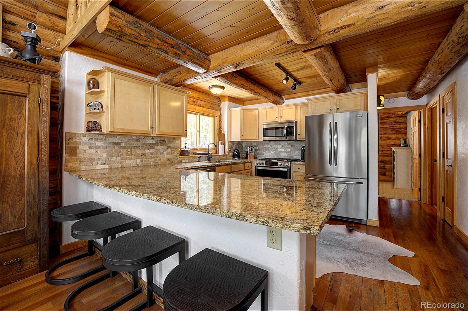 58 Conestoga Court Bailey, CO 80421 - Photo 8 of 37 a kitchen with stainless steel appliances granite countertop a table chairs and wooden floors