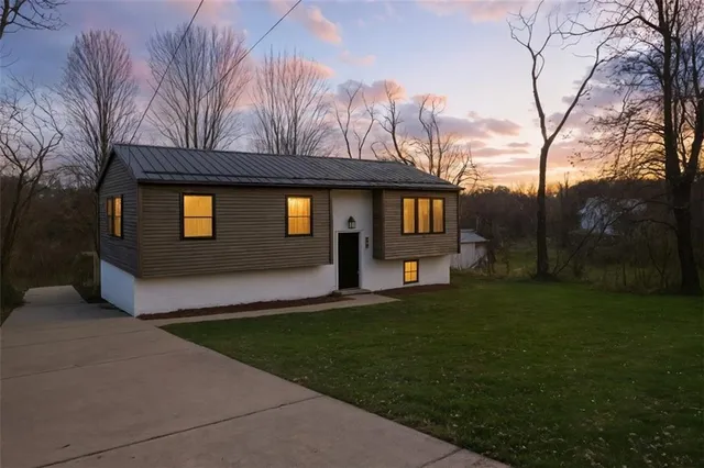 a front view of a house with a yard and trees