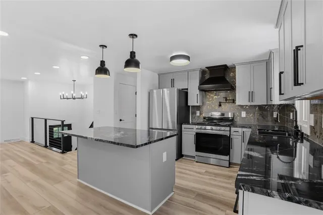 a kitchen with granite countertop a refrigerator stove top oven and sink