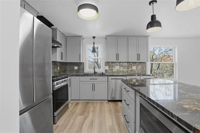 a kitchen with stainless steel appliances granite countertop a stove a sink and a refrigerator