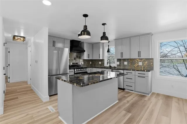 a kitchen with stainless steel appliances granite countertop a sink stove and refrigerator