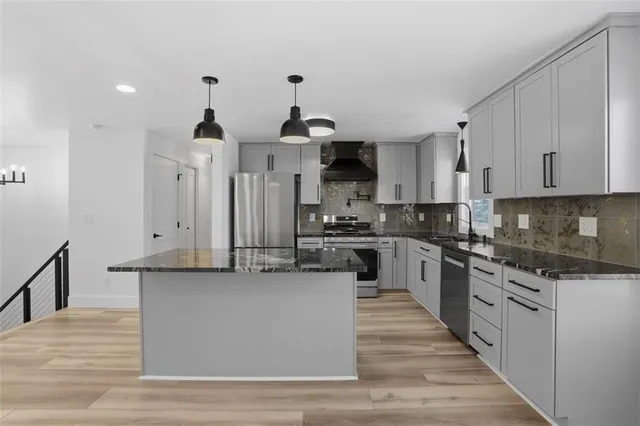 a kitchen with stainless steel appliances granite countertop a stove a sink and white cabinets