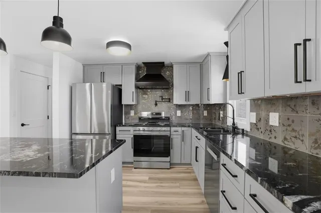 a kitchen with stainless steel appliances granite countertop a sink a stove and a refrigerator