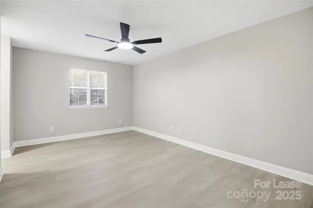 an empty room with a window and ceiling fan