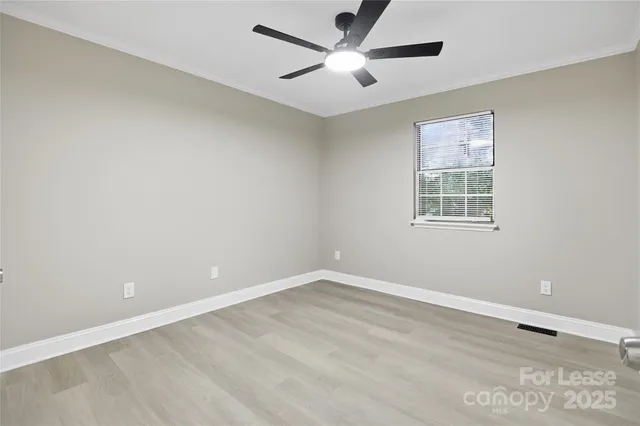 an empty room with a window and a fan