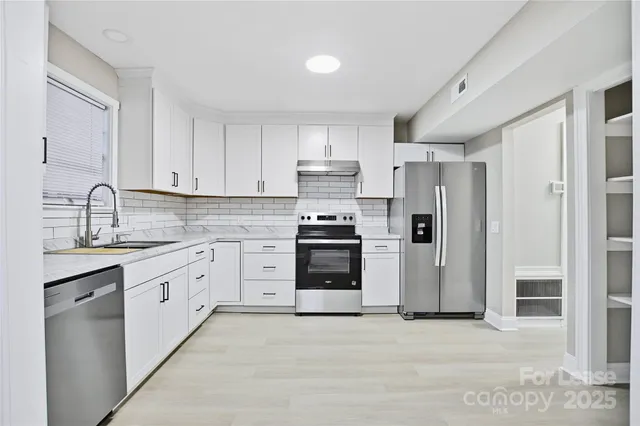 a kitchen with granite countertop white cabinets and stainless steel appliances