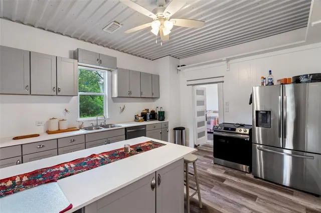 a kitchen that has a lot of cabinets a sink and appliances