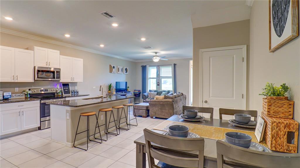 31632 Blue Passing Loop Wesley Chapel, FL 33545 - Photo 8 of 48 a kitchen with sink refrigerator dining table and chairs