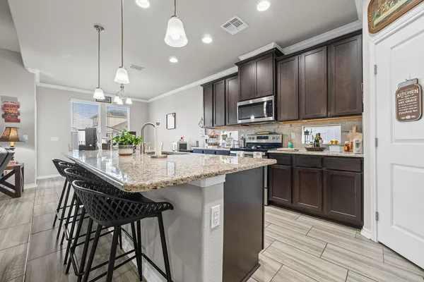a kitchen with granite countertop a refrigerator a sink and wooden floor