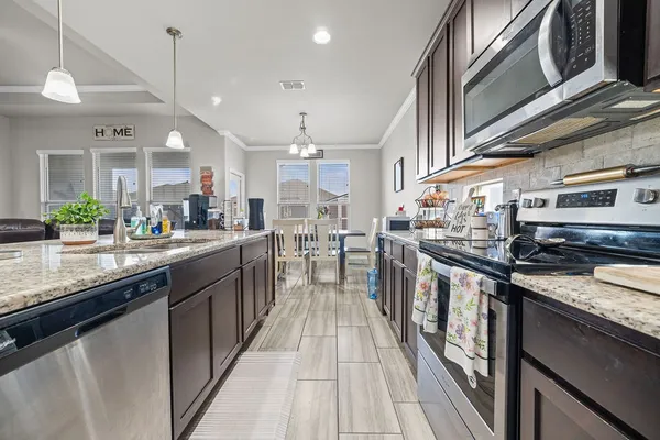 a kitchen with stainless steel appliances granite countertop a refrigerator a stove top oven and sink