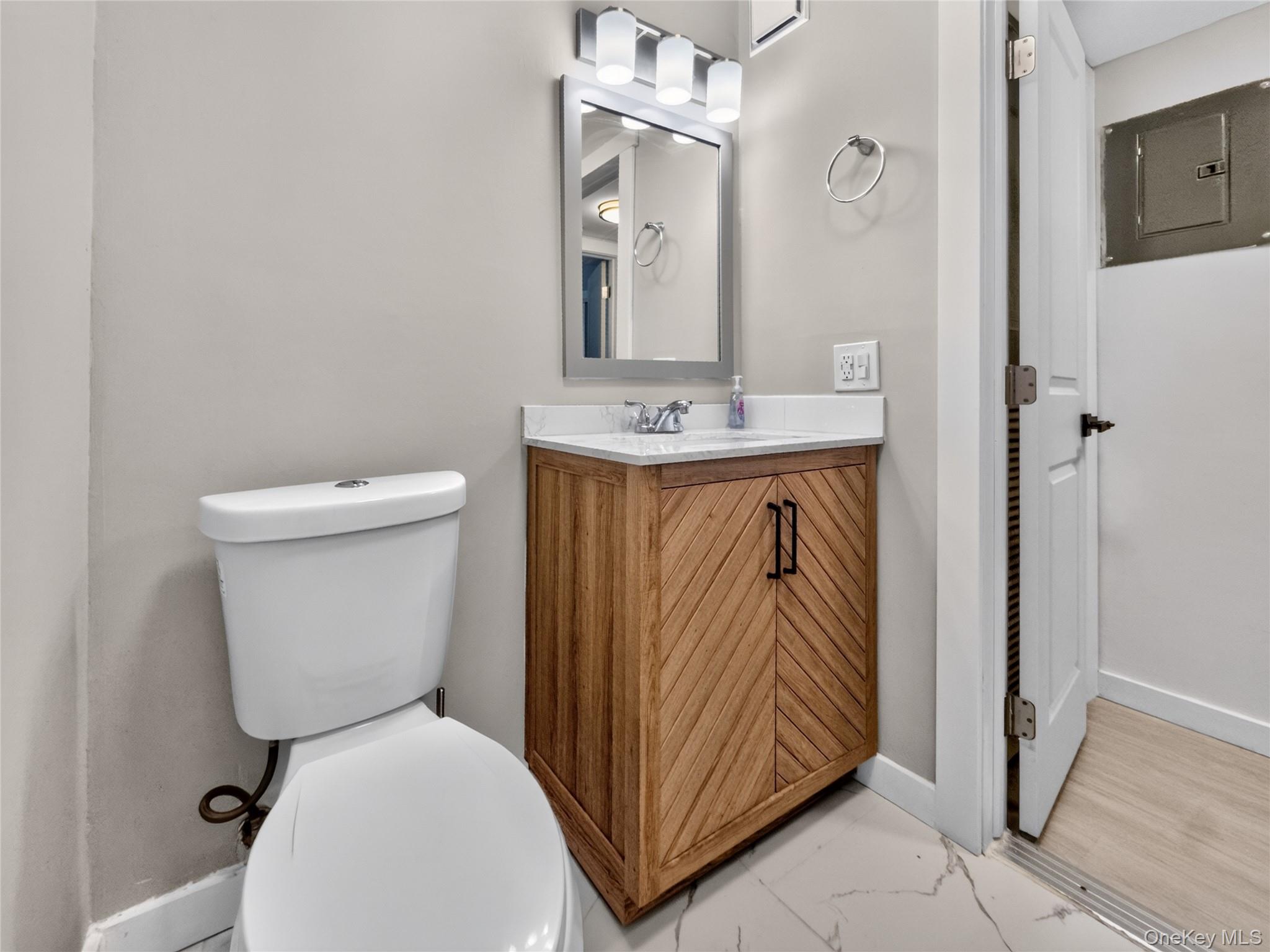 26 Cooper Road, Unit 414 Poughkeepsie, NY 12603 - Photo 20 of 24 Bathroom featuring a modern vanity with patterned wood-finish doors, a white countertop, and a rectangular sink with a chrome faucet
