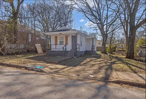 a front view of a house with yard tree and outdoor seating