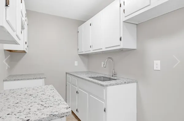 a kitchen with granite countertop white cabinets and a sink