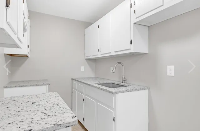 a kitchen with granite countertop white cabinets and a sink