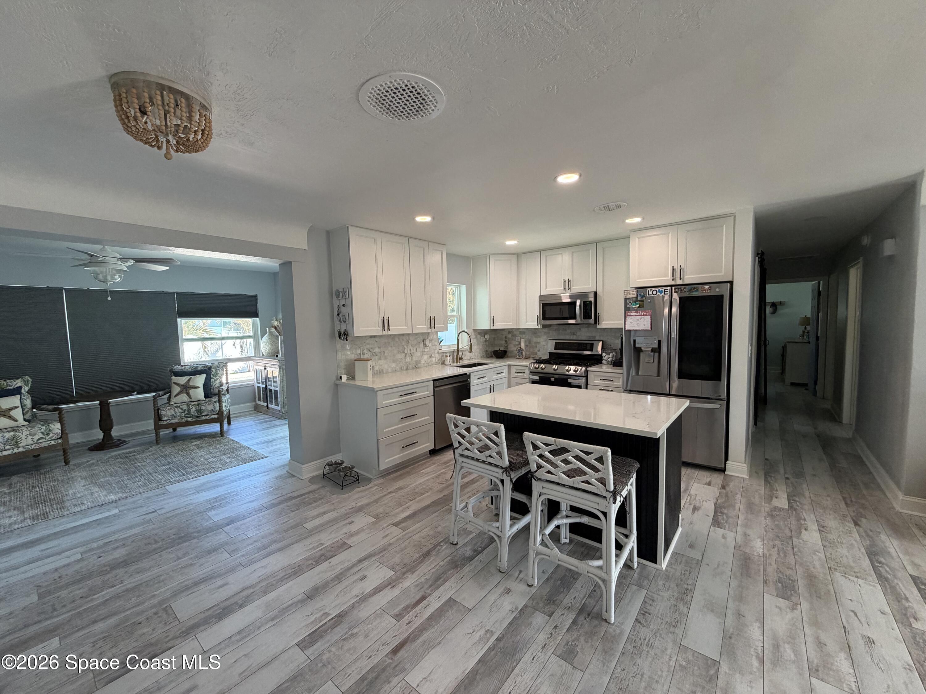 209 Southeast 3rd Street Satellite Beach, FL 32937 - Photo 4 of 25 a living room with stainless steel appliances furniture wooden floor and a kitchen view