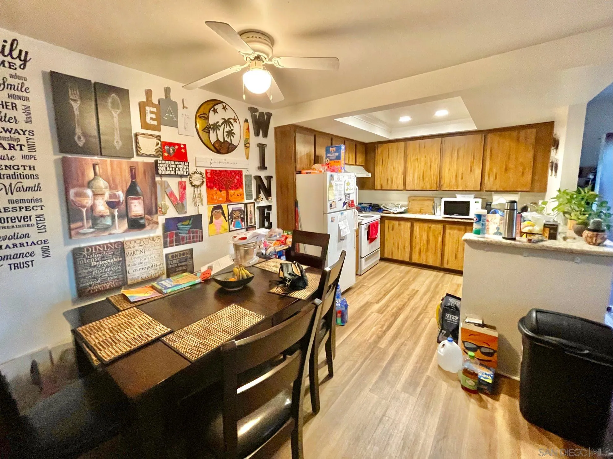 5970 Rancho Mission Road, Unit 244 San Diego, CA 92108 - Photo 6 of 21 a view of a dining room and livingroom with furniture wooden floor a rug a flat screen tv a painting and a chandelier