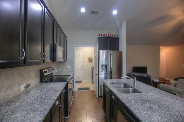 a kitchen with stainless steel appliances granite countertop a stove a sink and a refrigerator