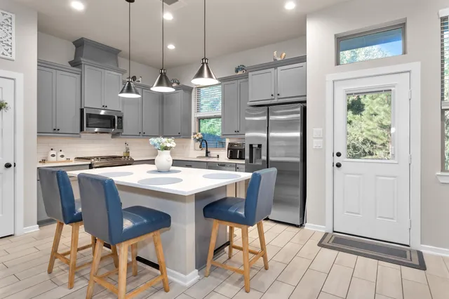 a kitchen with stainless steel appliances granite countertop a refrigerator a sink a stove a dining table and chairs