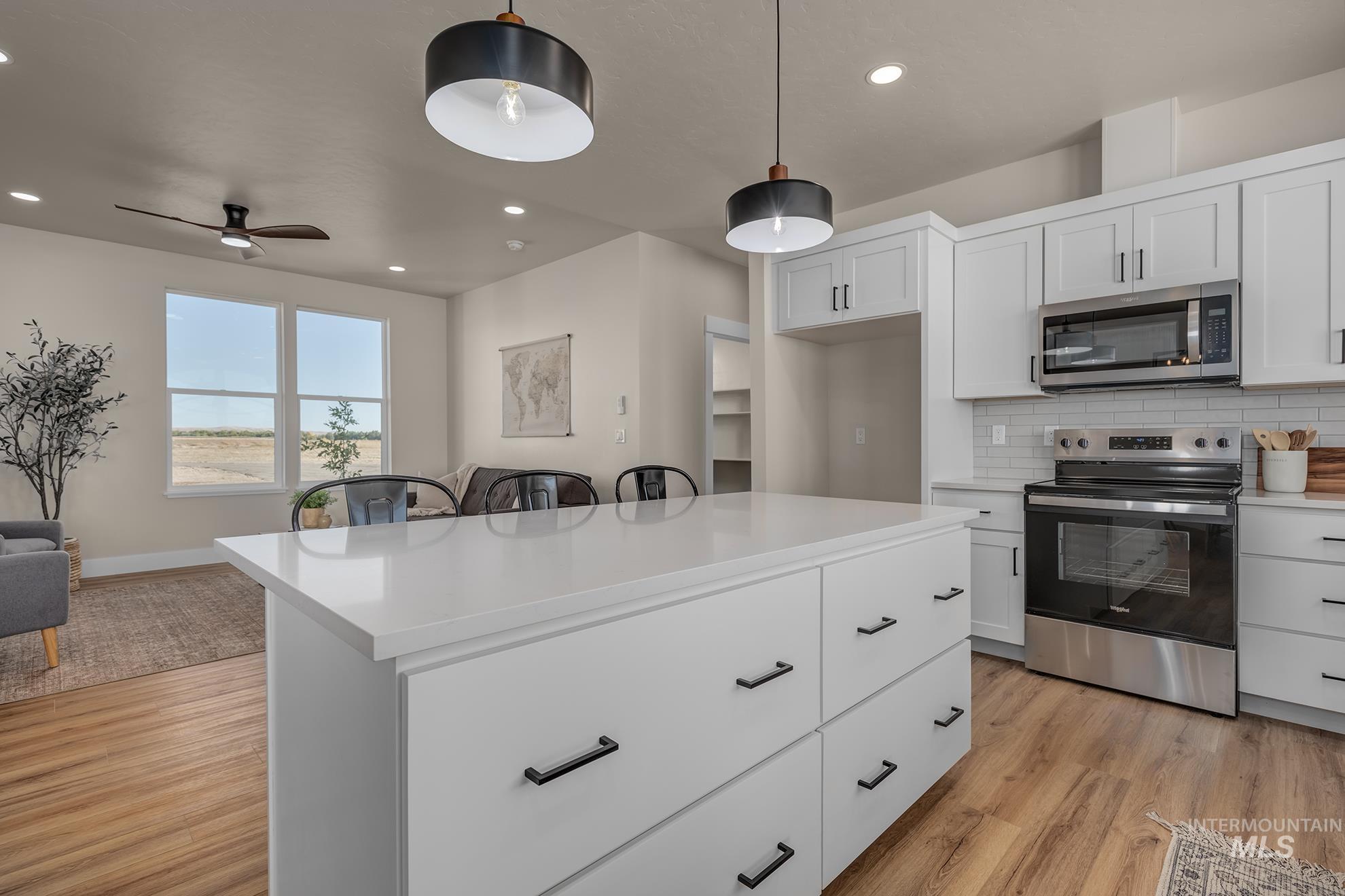 1371 Hansen Road Weiser, ID 83672 - Photo 14 of 44 Kitchen island with a white countertop and black hardware, white cabinetry, stainless steel appliances, and wood-finish flooring