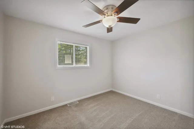 an empty room with a window and a fan