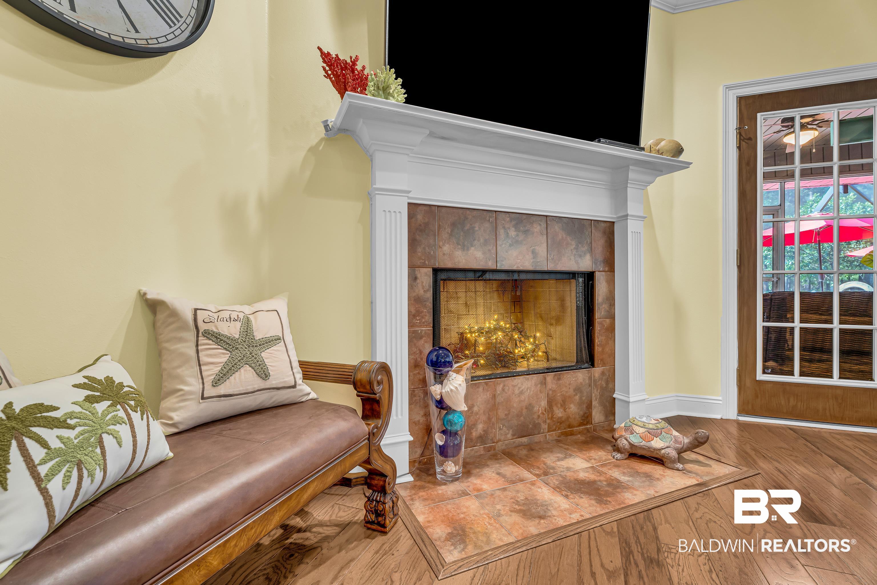 7014 Blakeley Road Daphne, AL 36527 - Photo 40 of 45 Fireplace with a white mantel and a tiled surround, complemented by wood-finish flooring