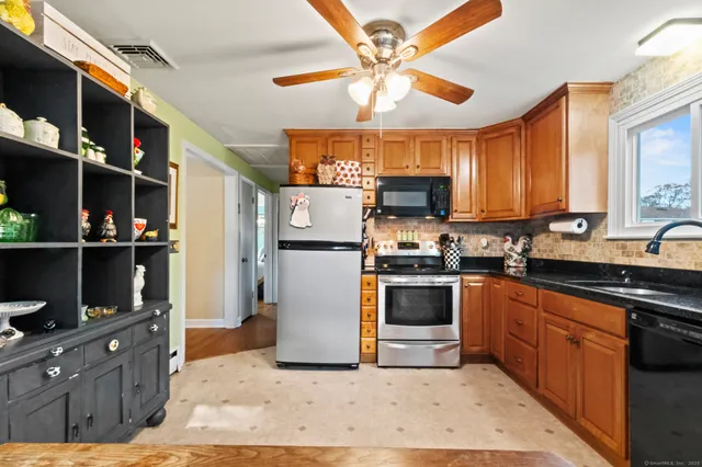 a kitchen with stainless steel appliances granite countertop a refrigerator a sink dishwasher a stove and a refrigerator