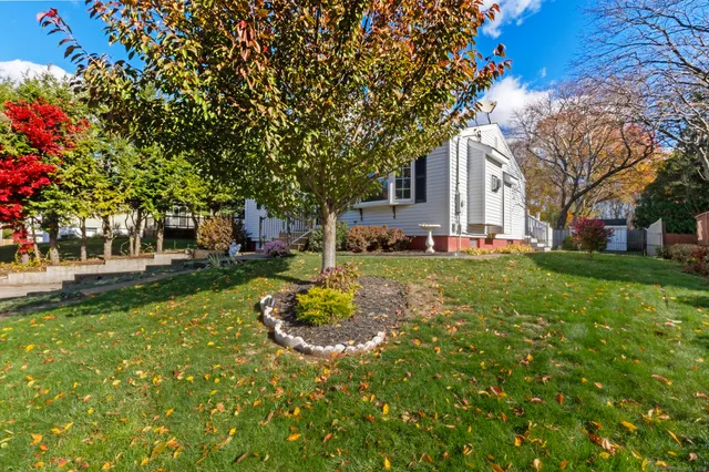 a view of a house with a big yard and large tree