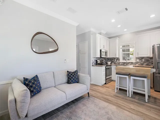 a living room with furniture a kitchen island with wooden cabinets and floor