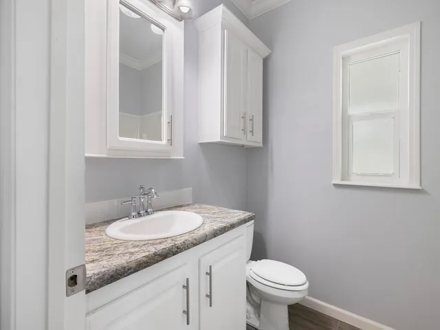 a bathroom with a granite countertop sink and a toilet
