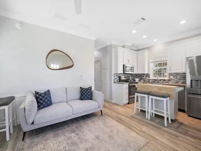 a living room with stainless steel appliances kitchen island granite countertop furniture and a wooden floor