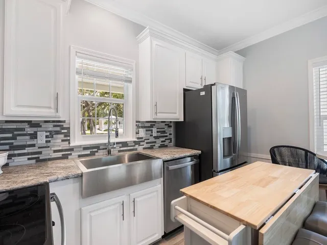 a kitchen that has a sink a stove a refrigerator and white cabinets